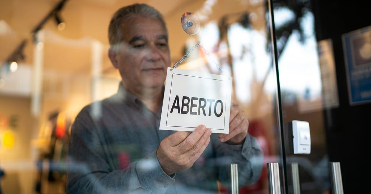 Shop owner hanging an open sign on the glass door of a high street shop